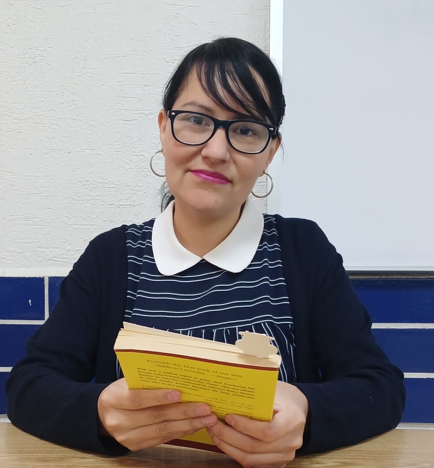 La Mtra. Lenia Rosas Brugada sosteniendo un libro con una sonrisa serena