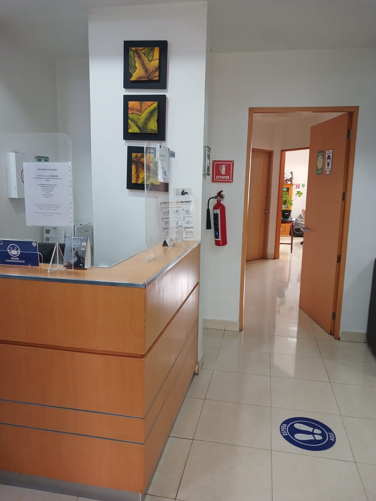 Recepción del consultorio con mostrador de madera y señalización clara